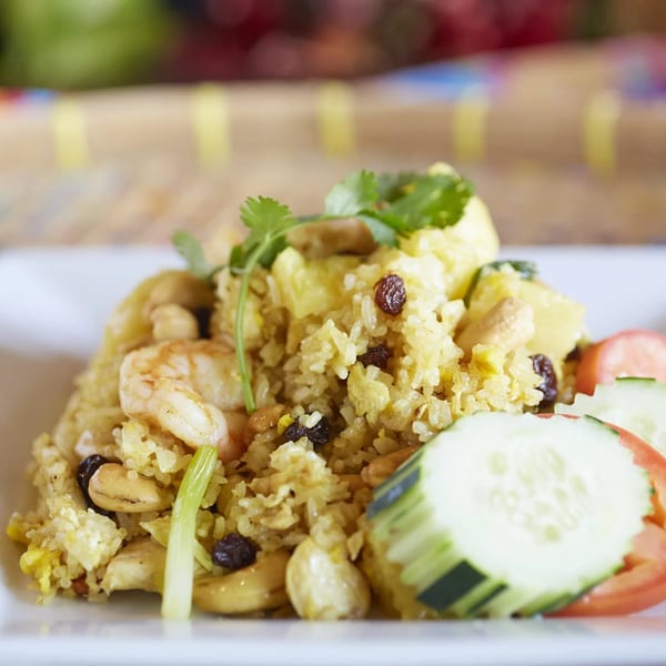 Golden fried rice with shrimp, cashews, raisins, pineapple, and fresh cucumber and tomato slices.